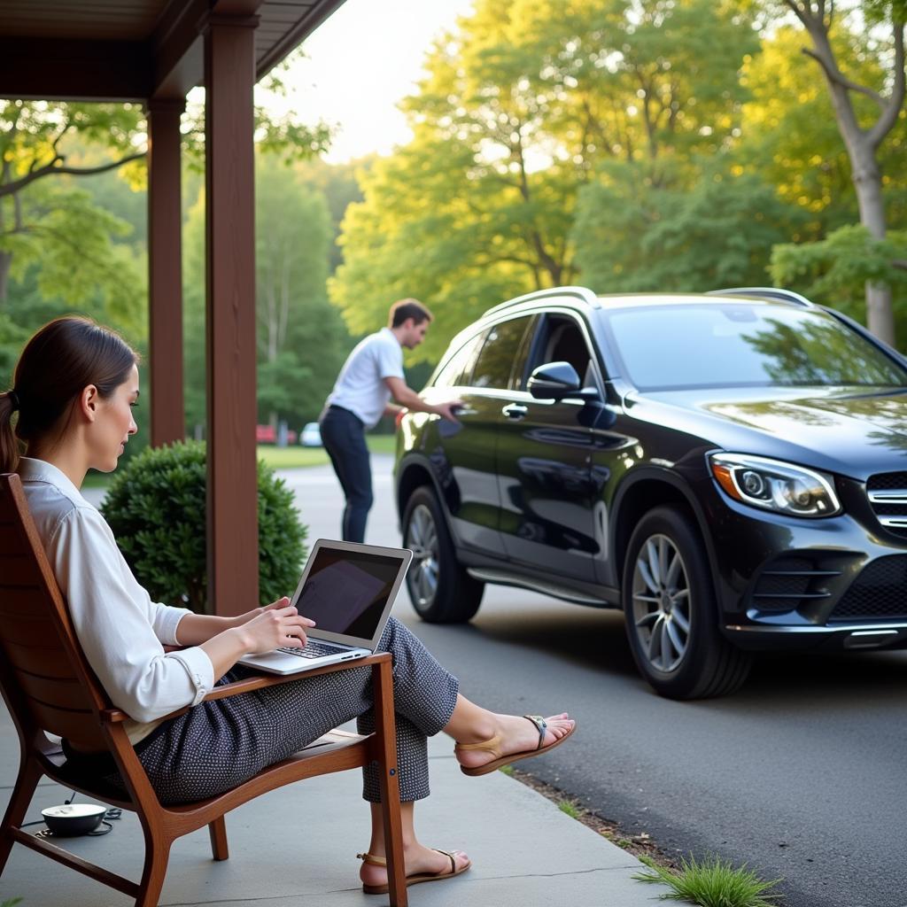 Benefits of Mobile Car Detailing in Newcastle: A person working on their laptop while their car is being detailed in their driveway.