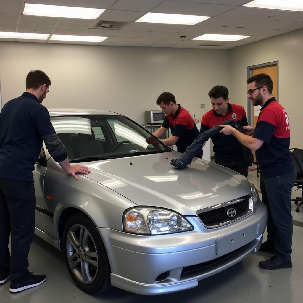 Students practicing car detailing techniques in a training class