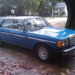 Front quarter view of a blue 1983 Mercedes-Benz 300DT, showcasing its classic W123 body style and original sealed beam headlights, parked on a paved surface.