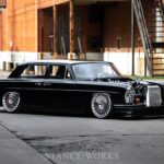 Front three-quarter view of a lowered, modified 1969 Mercedes 280S showcasing its custom wheels and aggressive stance.