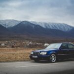 Front three quarter view of a dark blue Mercedes-Benz E60 AMG parked outdoors, showcasing its classic sedan silhouette.