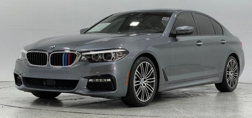 BMW 5 Series 540i xDrive in black, parked in a dealership setting