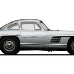 1955 Mercedes-Benz 300 SL Gullwing in silver, showcasing its iconic gullwing doors and Rudge wheels, parked outdoors with trees in the background.