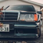 Front three-quarter view of a black Mercedes 190E Evolution II parked outdoors, showcasing its boxy design and prominent rear wing.