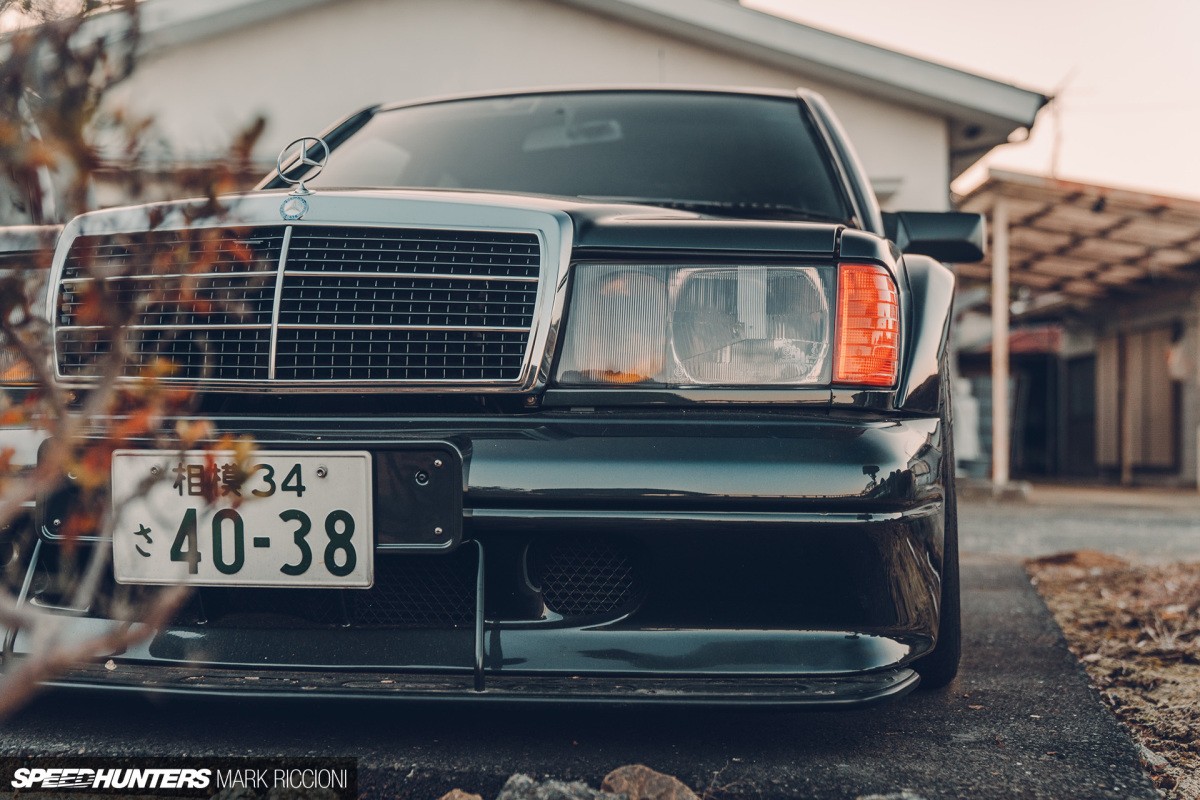 Front three-quarter view of a black Mercedes 190E Evolution II parked outdoors, showcasing its boxy design and prominent rear wing.