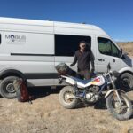 Ian standing next to a Yamaha dirtbike and a Mercedes Sprinter van, highlighting the van's size in relation to a person and motorcycle.