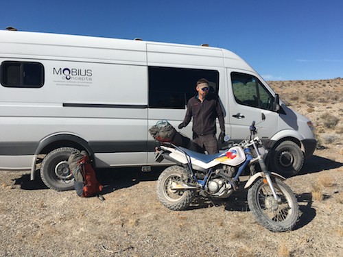 Ian standing next to a Yamaha dirtbike and a Mercedes Sprinter van, highlighting the van's size in relation to a person and motorcycle.