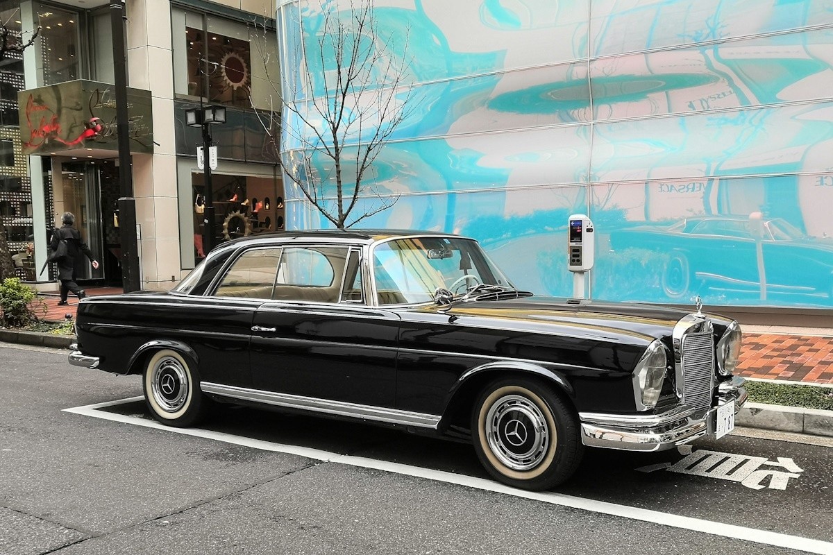 Front quarter view of a black Mercedes-Benz 220 Classic Coupe showcasing its Euro headlights and elegant design