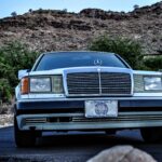 Front three quarter view of a 1990 Mercedes 300E showcasing its classic grille, headlights, and bumper design.