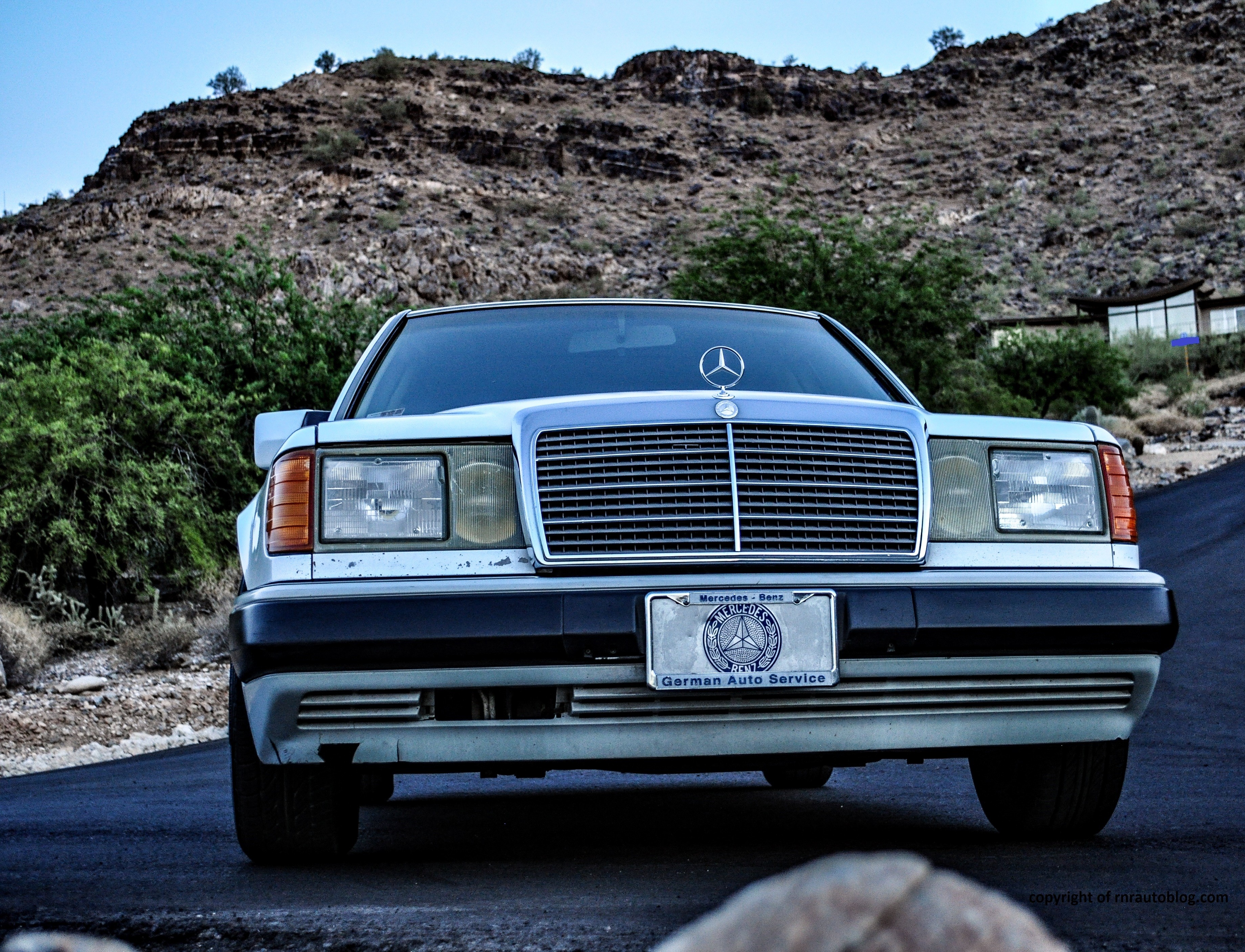 Front three quarter view of a 1990 Mercedes 300E showcasing its classic grille, headlights, and bumper design.