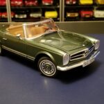 Front three quarter view of the Moosgrun metallic Schuco 1968 Mercedes 280SL model car showcasing its detailed grille and headlights.