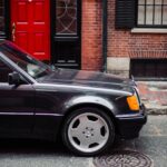 Front profile of a black 1992 Mercedes-Benz 500E, showcasing its wider fenders. Keywords: 1992 Mercedes-Benz 500E, front profile, black, wider fenders, classic Mercedes